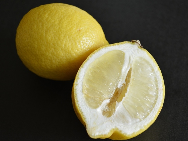 Целый лимон и половина на черной поверхности