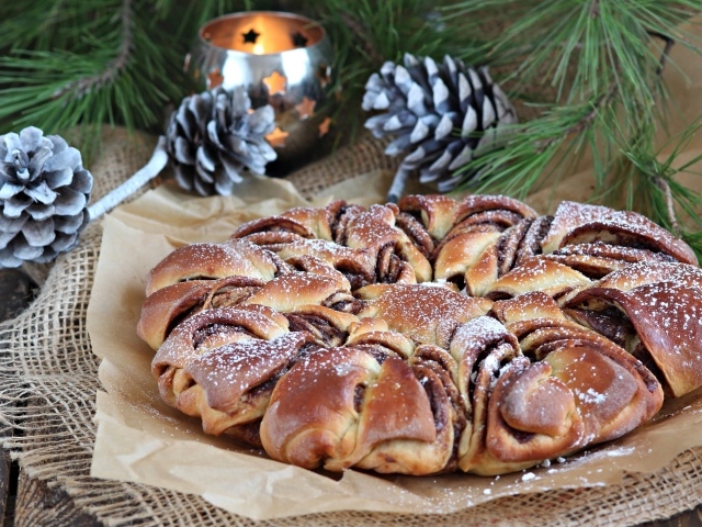 Сдобный венок с вареньем на столе с шишками