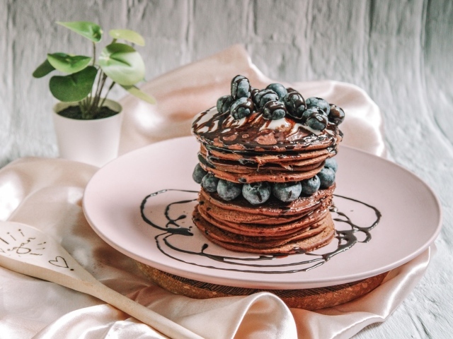 Шоколадные оладьи с ягодами черники на белой тарелке