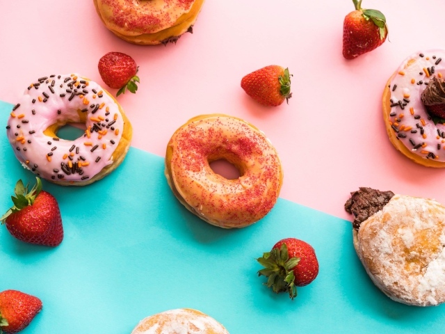 Пончики с глазурью на столе с ягодами клубники