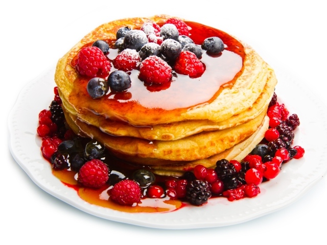 Оладьи с медом и ягодами малины и черники на белом фоне