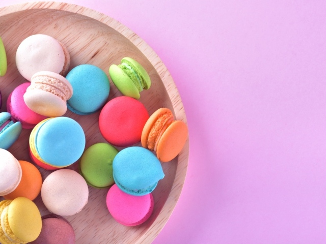 Разноцветное печенье макарон на розовом фоне вид сверху