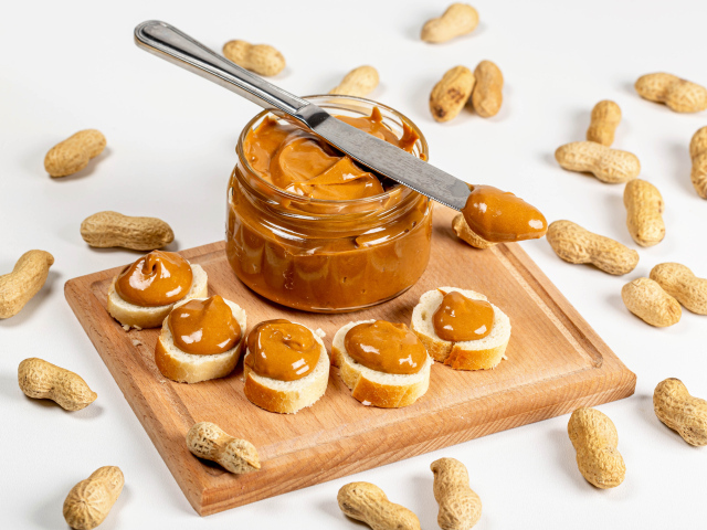 Ореховая паста на столе с батоном и арахисом