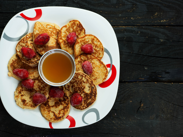 Оладьи на тарелке с клубникой и медом