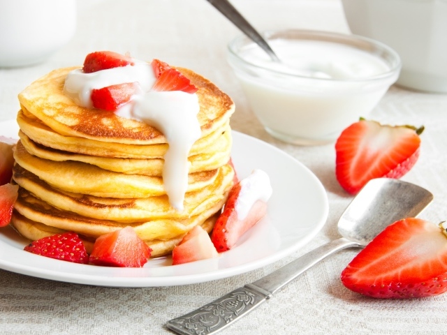 Оладьи с клубникой и сметаной на столе