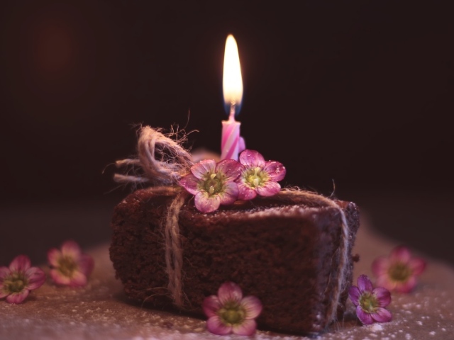 Кусок торта на столе с розовыми цветами и свечкой