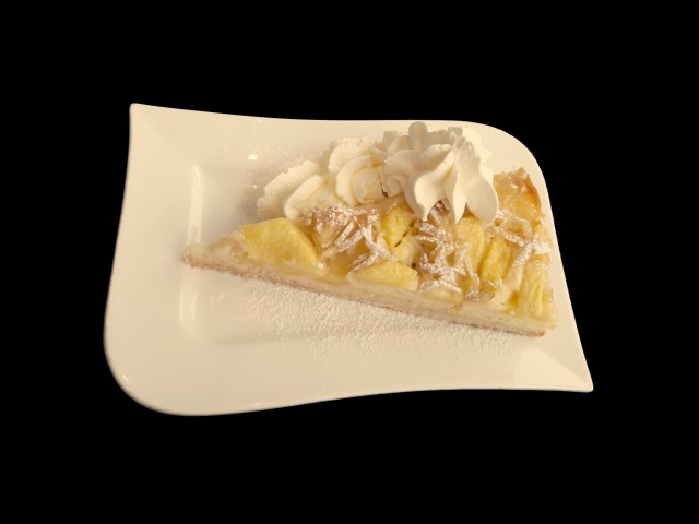 Кусок пирога с фруктами в белой тарелке на черном фоне