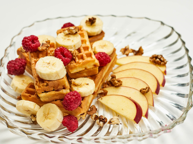 Сладкие вафли на тарелке с бананом, малиной и яблоком