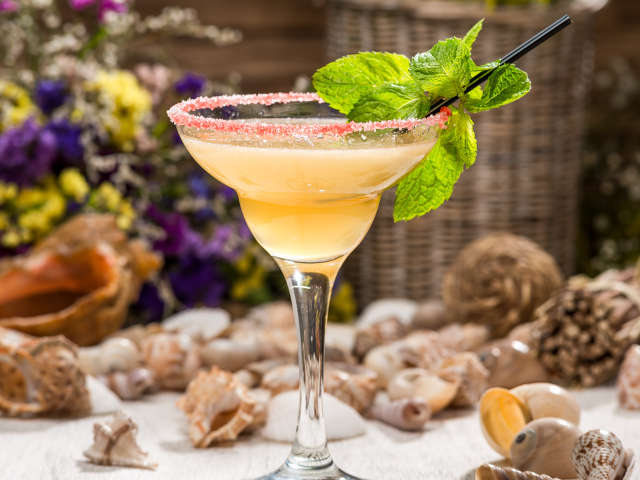 Коктейль с мятой в бокале на столе с ракушками 