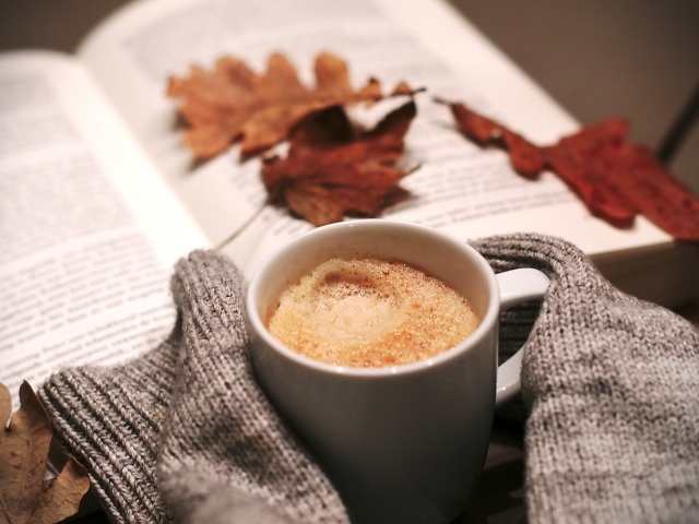 Чашка горячего кофе на столе с книгой 