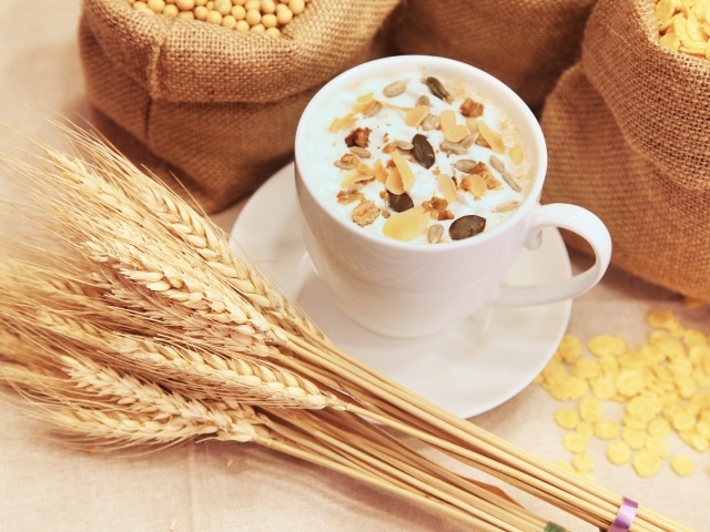 Чашка молока с мюсли на столе с колосками