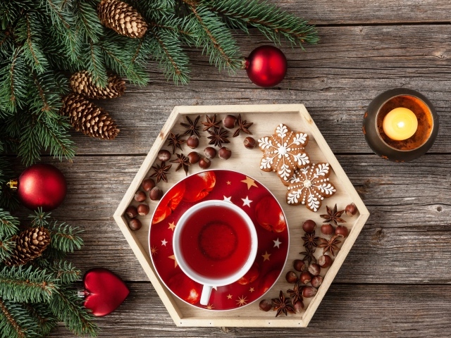 Чашка чая с печеньем и орехами на столе с еловой веткой