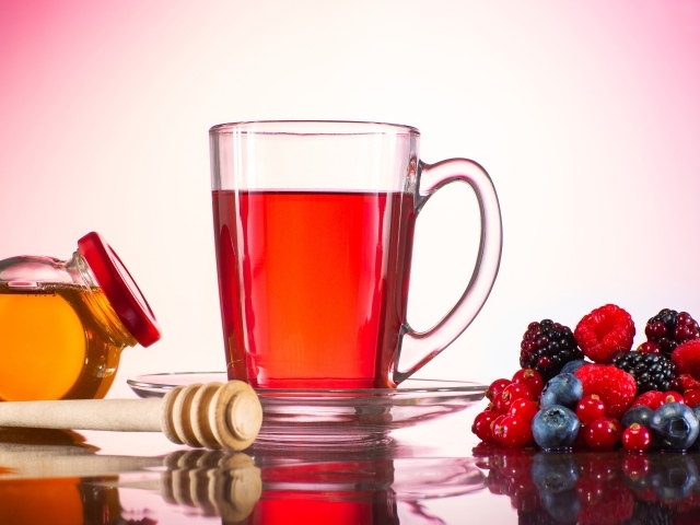 Чашка чая с медом на столе с ягодами
