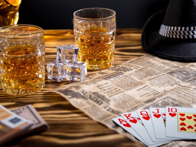 Виски со льдом на столе с картами, газетой и шляпой