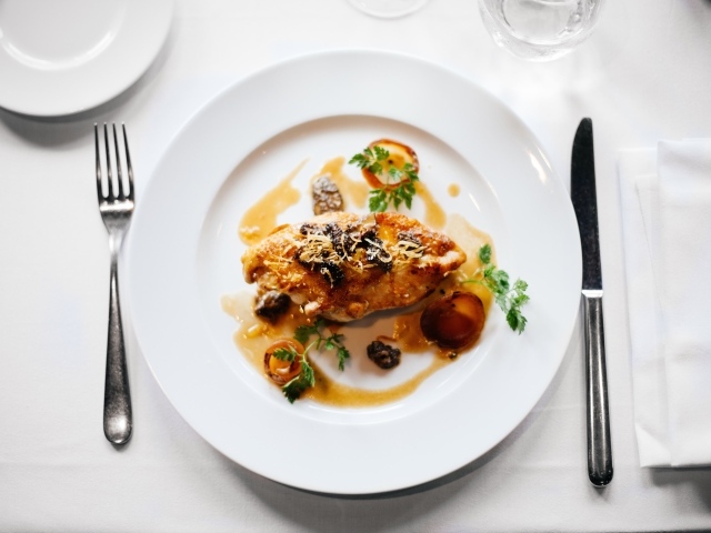 Кусок жареного мяса на большой белой тарелке 