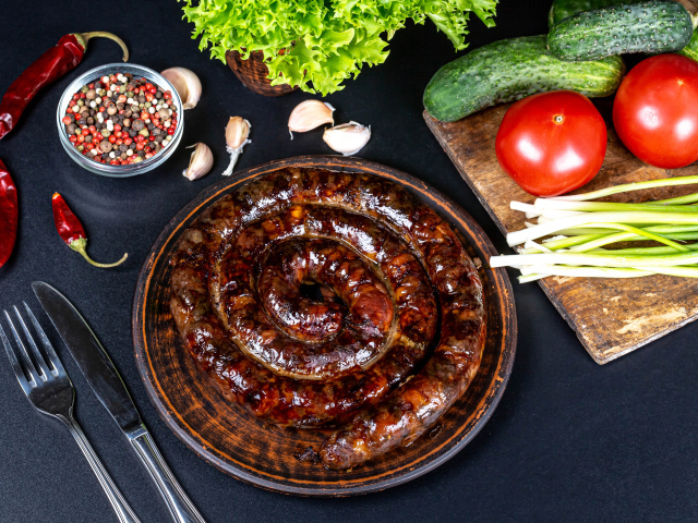 Аппетитная домашняя колбаса на столе со специями и овощами