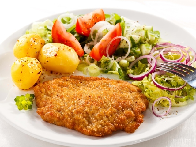 Отбивная с курицы на тарелке с картофелем и овощами 