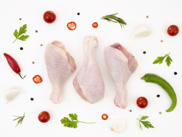 Свежие куриные бедра с перцем и помидорами на белом фоне 