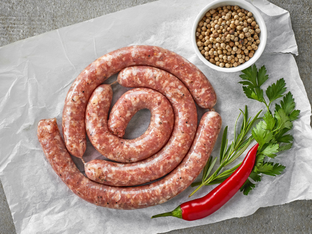 Домашняя колбаса на столе с зеленью и перцем