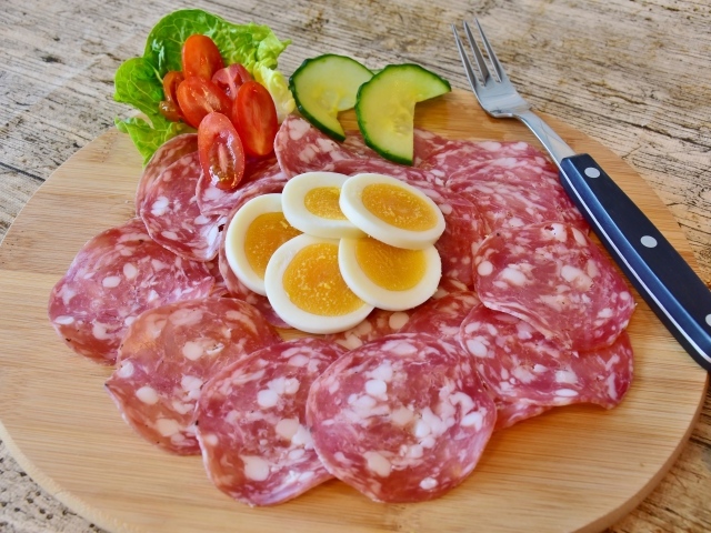 Колбаса салями на доске с яйцами и овощами