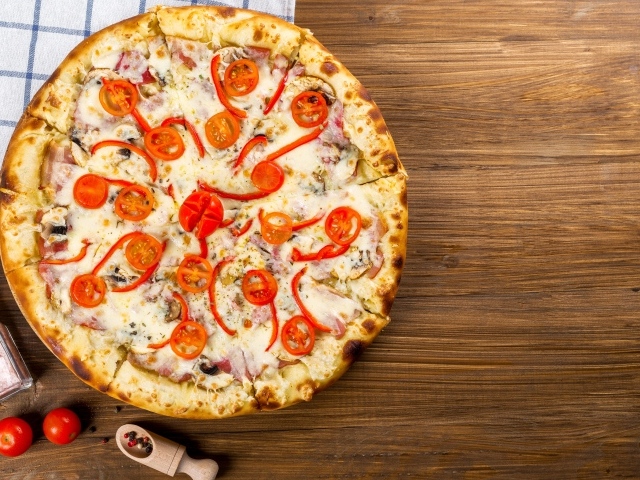 Пицца с беконом на столе с помидорами  и перцем