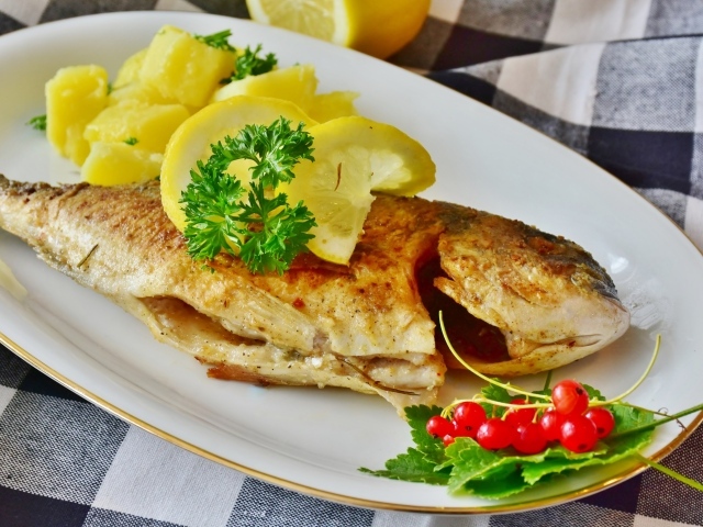 Жареная рыба с лимоном на тарелке с картофелем