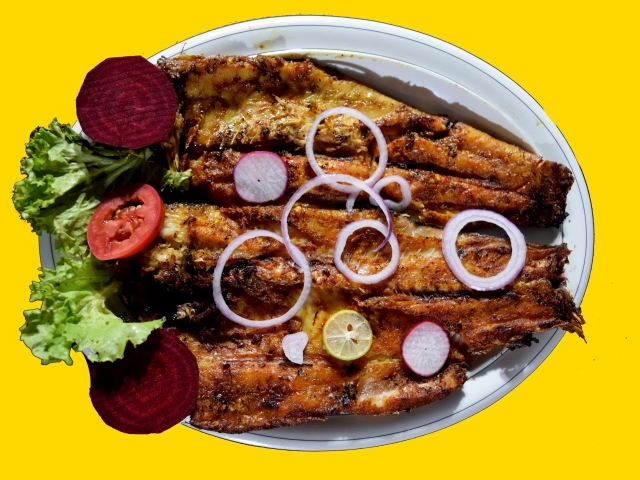 Жареная рыба с листьями салата, помидорами и свеклой на желтом фоне