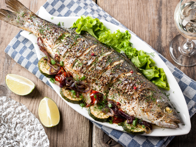 Большая запеченная рыба с кабачками и листьями салата