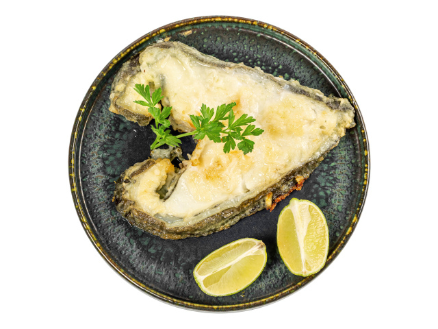 Кусок рыбы на тарелке с лимоном на белом фоне