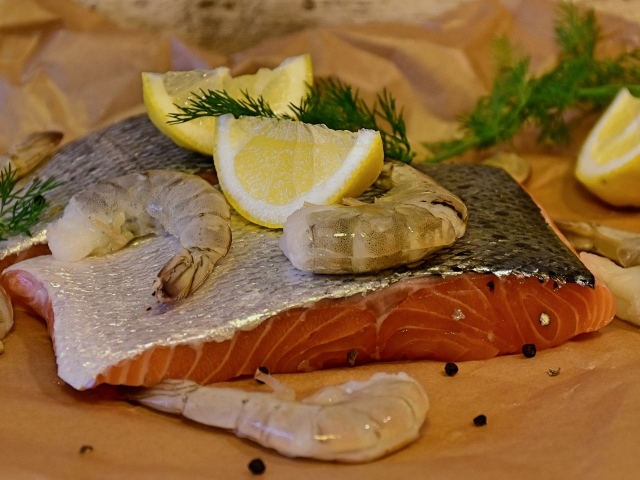 Кусок красной рыбы с креветками и лимонами