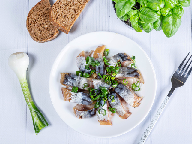 Куски скумбрии на столе с луком, хлебом и базиликом