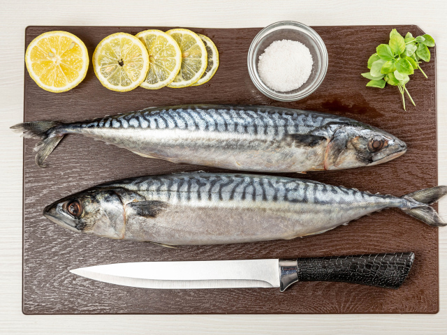 Две свежие скумбрии на доске с лимоном 