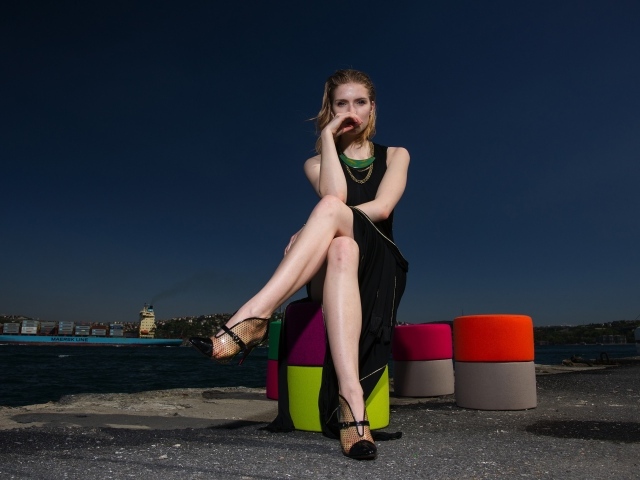 Девушка в черном платье сидит у воды