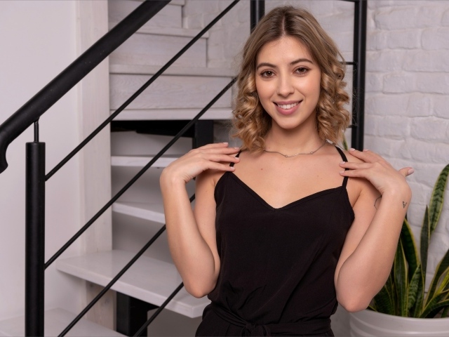 Девушка в черном платье стоит у ступеней