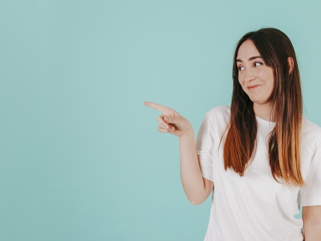 Девушка в белой футболке показывает на кого то пальцем