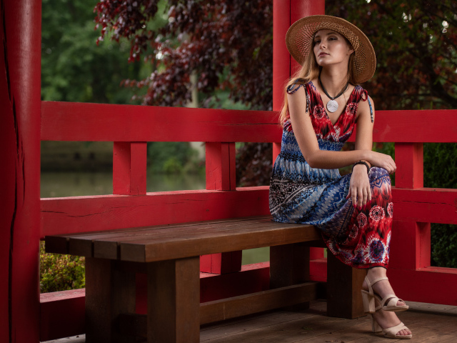 Молодая девушка в платье сидит на лавке 