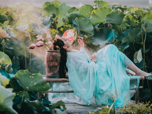 Девушка азиатка в красивом голубом платье на поле лотосов