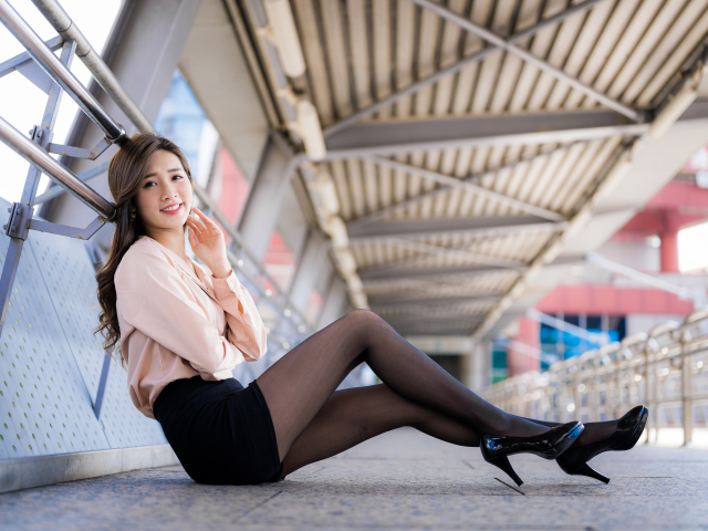 Девушка азиатка в черной юбке сидит в переходе 