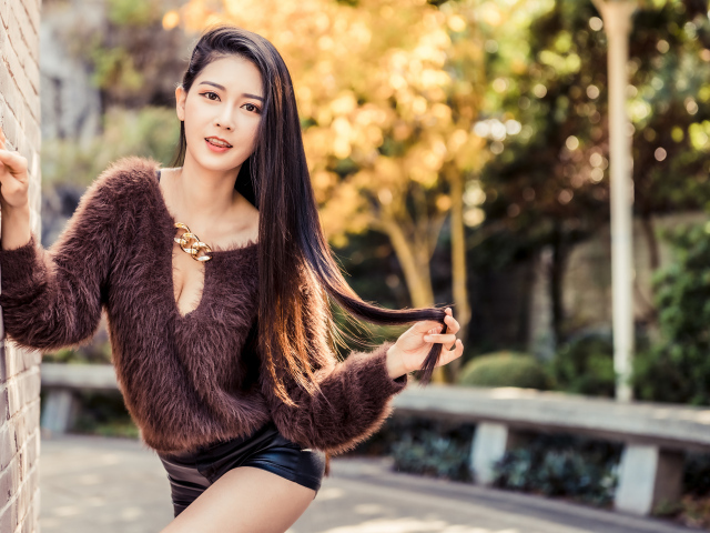 Девушка азиатка в черных шортах у стены