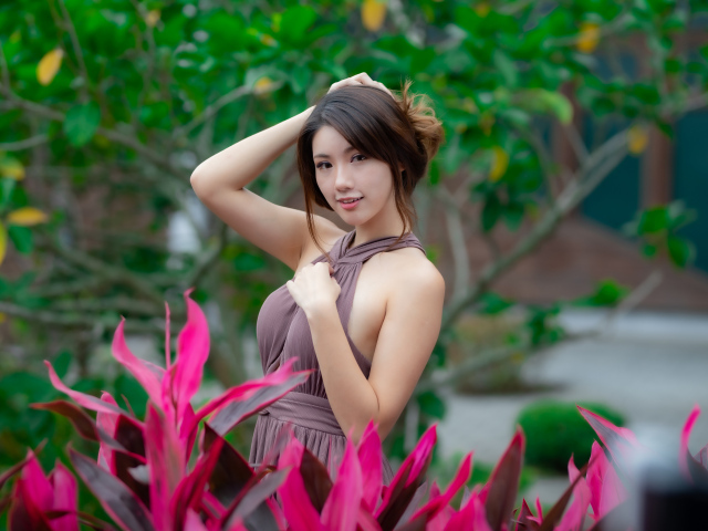 Красивая девушка азиатка в платье у красных цветов