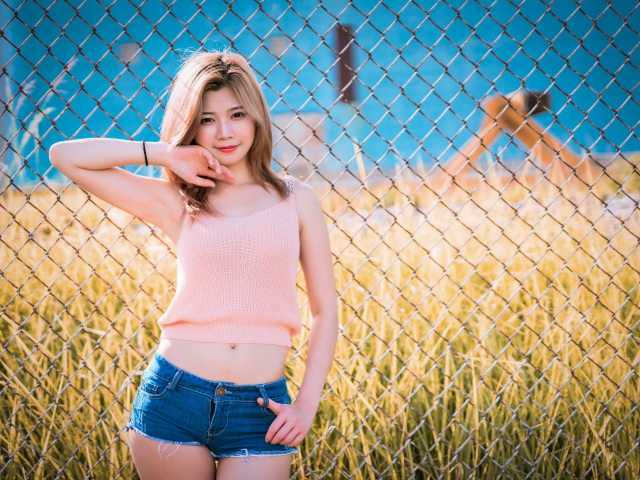 Красивая девушка азиатка стоит у железной сетки