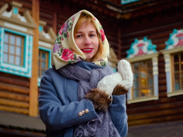 Красивая русская женщина в платке стоит у дома