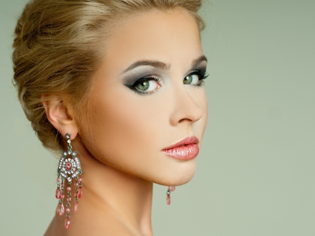 Красивая девушка блондинка с красивыми сережками на сером фоне