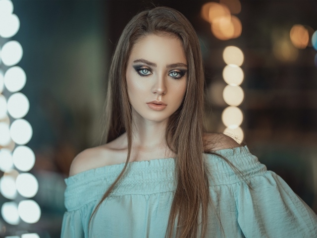 Красивая голубоглазая девушка в платье у зеркала 