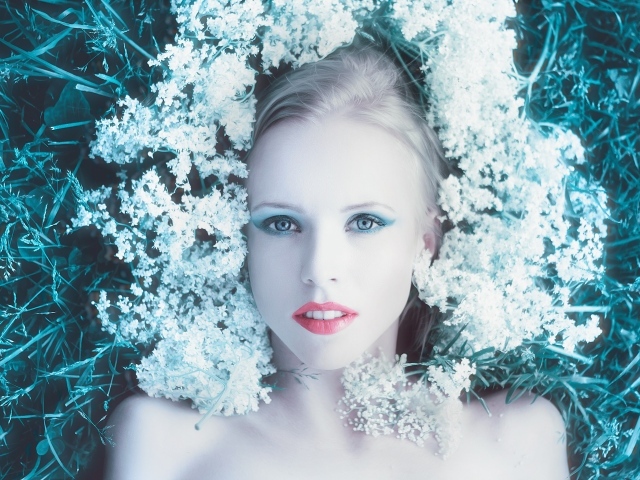 Красивая голубоглазая девушка на траве с белыми цветами