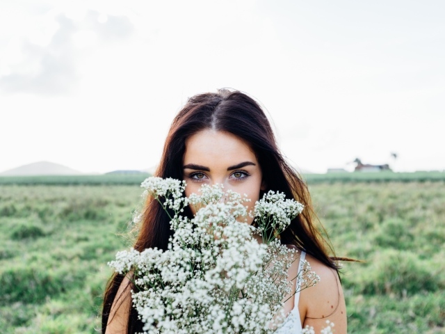 Красивая кареглазая девушка с букетом белых полевых цветов 