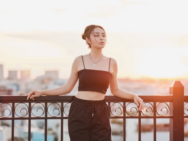 Красивая девушка в черном костюме на мосту в лучах солнца