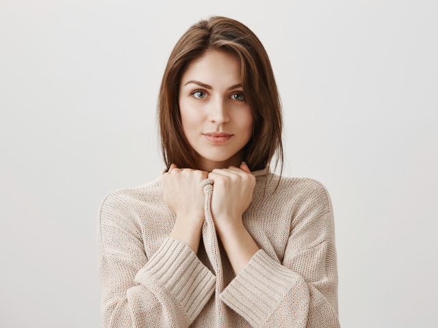 Красивая девушка в теплом свитере на сером фоне 