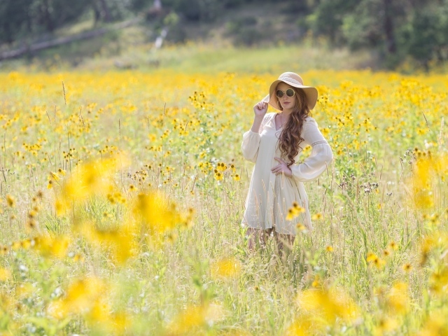 Красивая девушка в белом платье и шляпе на поле с желтыми цветами
