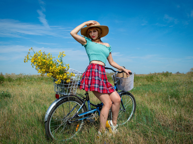 Красивая девушка на велосипеде на поле 
